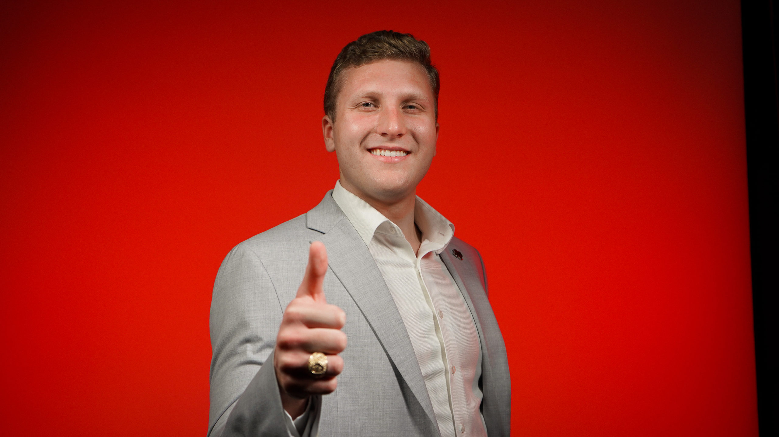 young man with gig 'em thumb up on red background