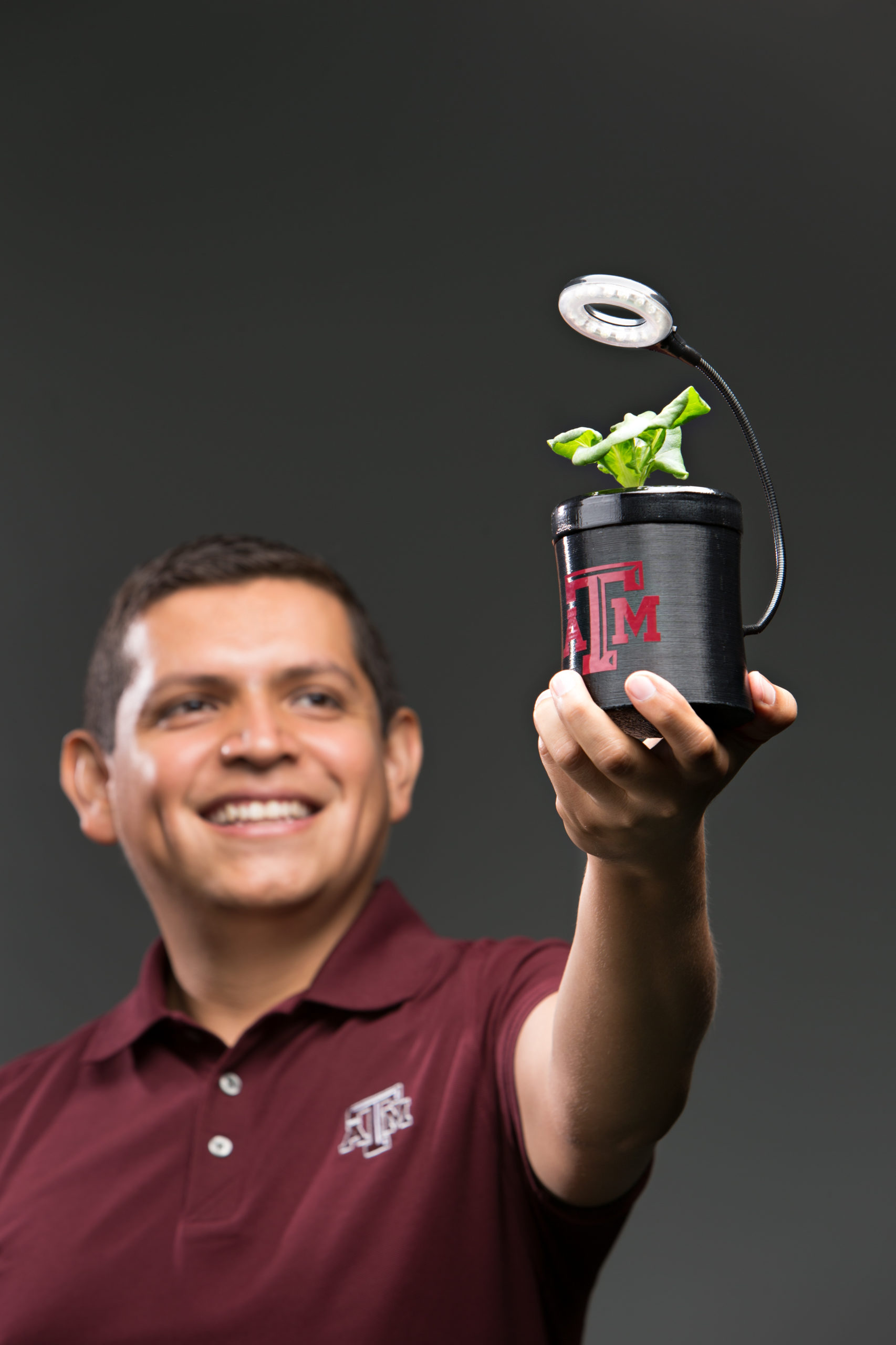 Alfredo Costilla Reyes holding a BitGrange device with a newly sprouted plant. The device is a small cyliner and comes equipped with an individual LED light to help plant growth.