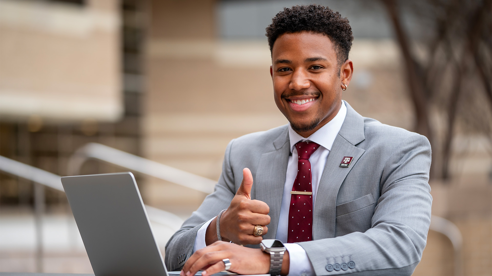 Business Student working on a laptop giving a thumbs up