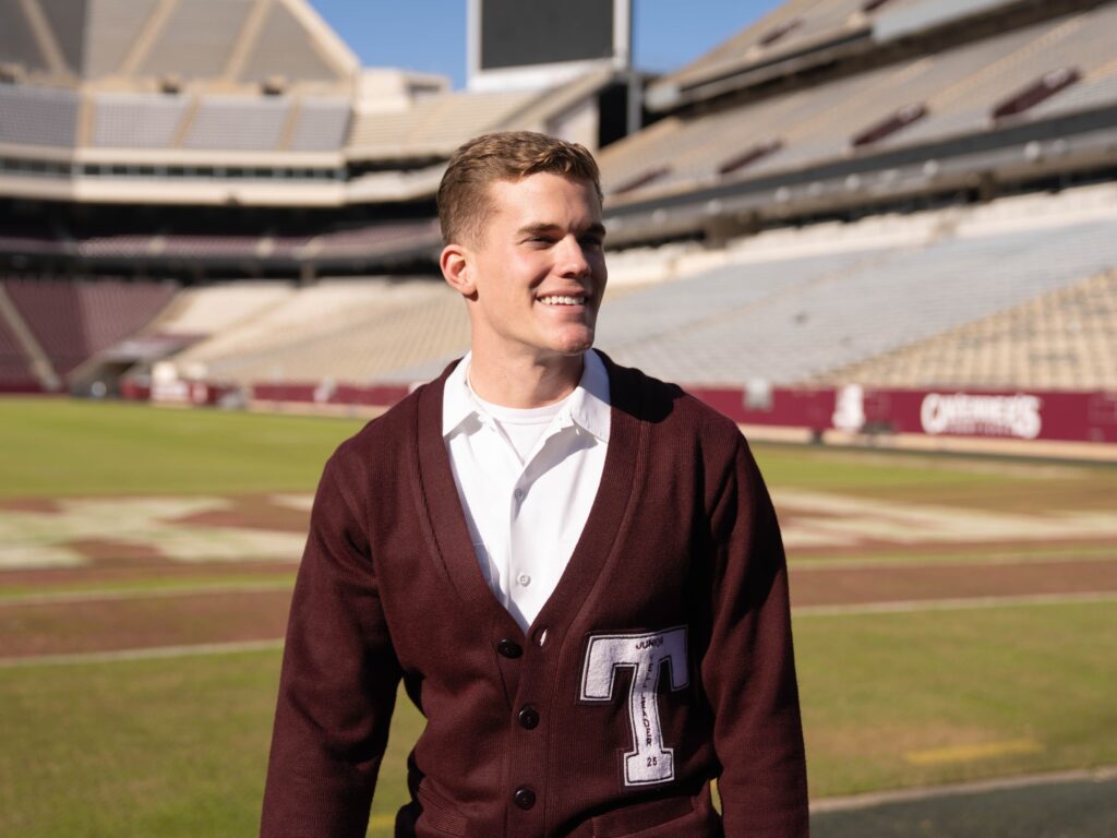 Yell leader in maroon sweater standing in football stadium