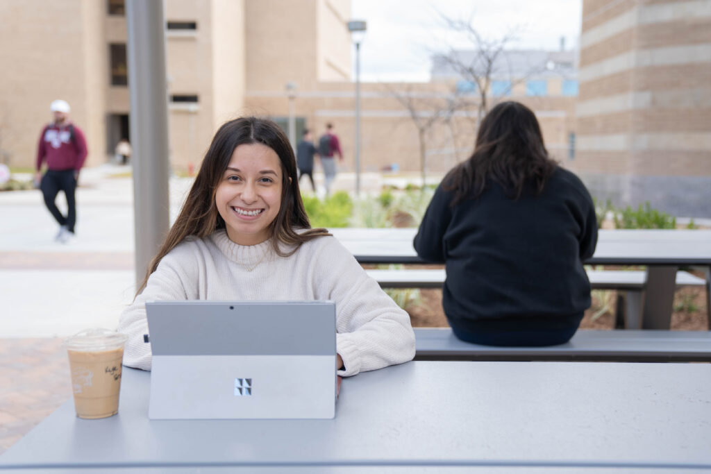 Students working on their laptops outside at tables