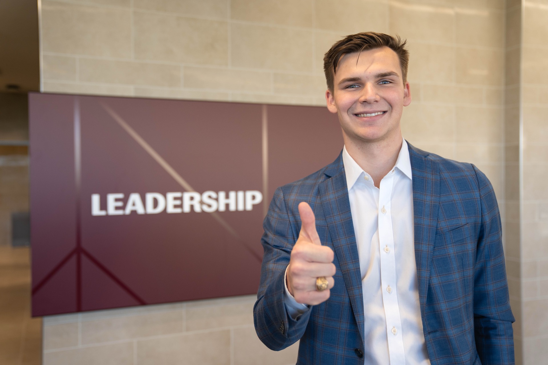 Cade Coppinger giving thumbs up in front of Leadership sign